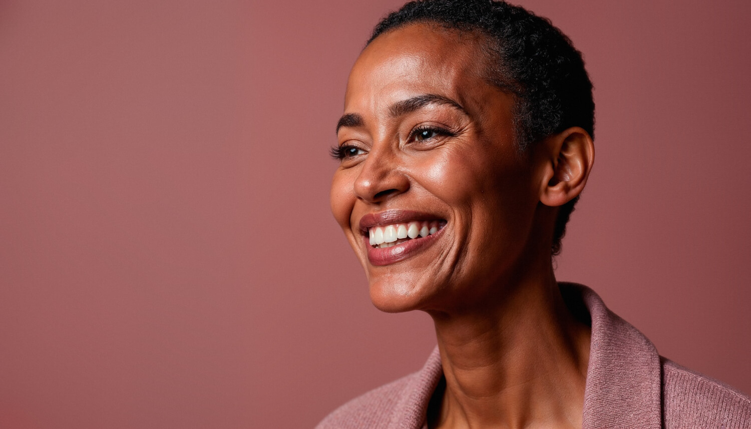 Mulher negra sorrindo confiante com dentes alinhados após tratamento com implante dentário na Sollis Odontologia em Jaguariúna.